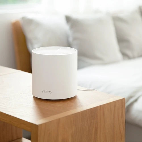 Dispositivo TP-Link Deco X50 sobre una mesa de madera en el dormitorio.